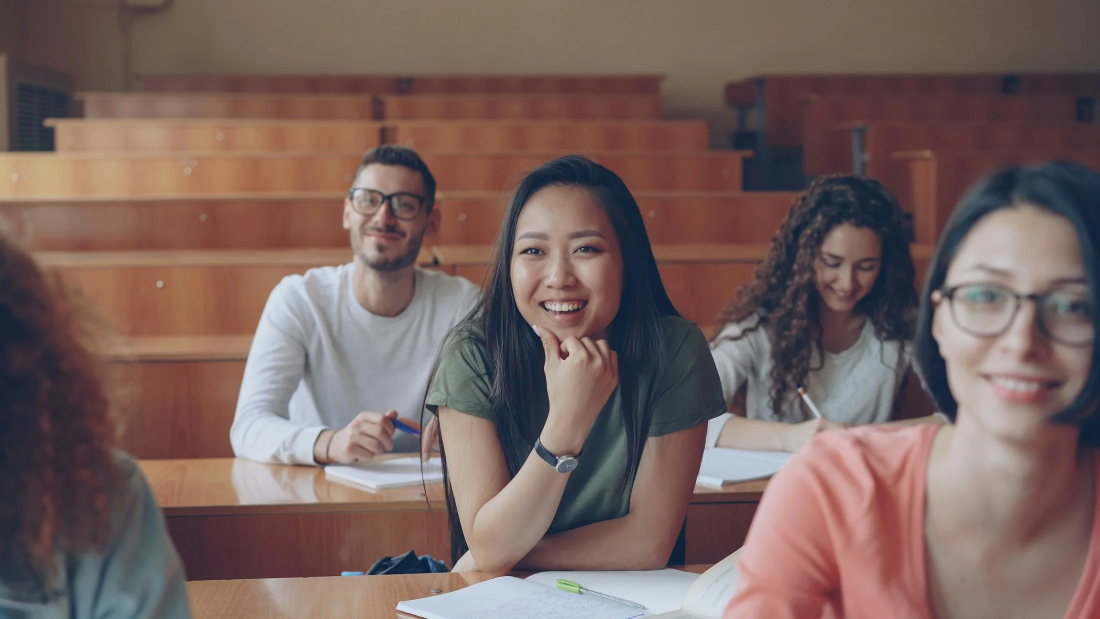 Smiling university students learning together in a lecture hall